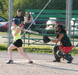 Nelson Missfits' batter Jessica Nowlan sends a shot into the infield, as Nelson Lady Vics catcher Chi Metallic looks on.