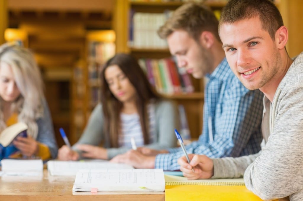 Smiling male student with friends at library