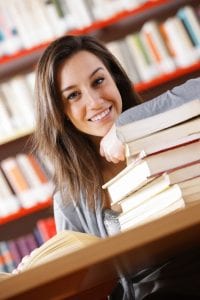 smiling college student with a stack of books