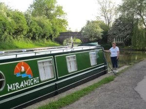 Jean Blanchard standing beside their narrowboat, "Miramichi", which they launched in 2013 at Crick near Northampton in the UK.